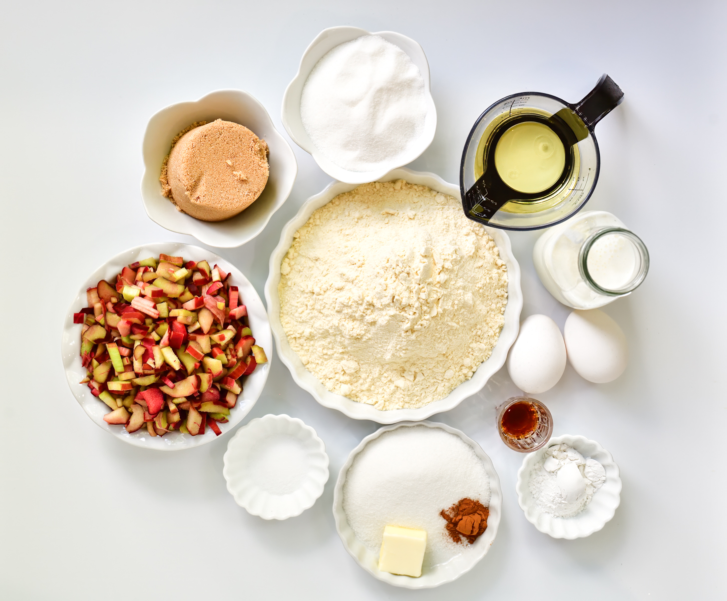 Rhubarb muffin Ingredients in white bowls arranged on a white background
