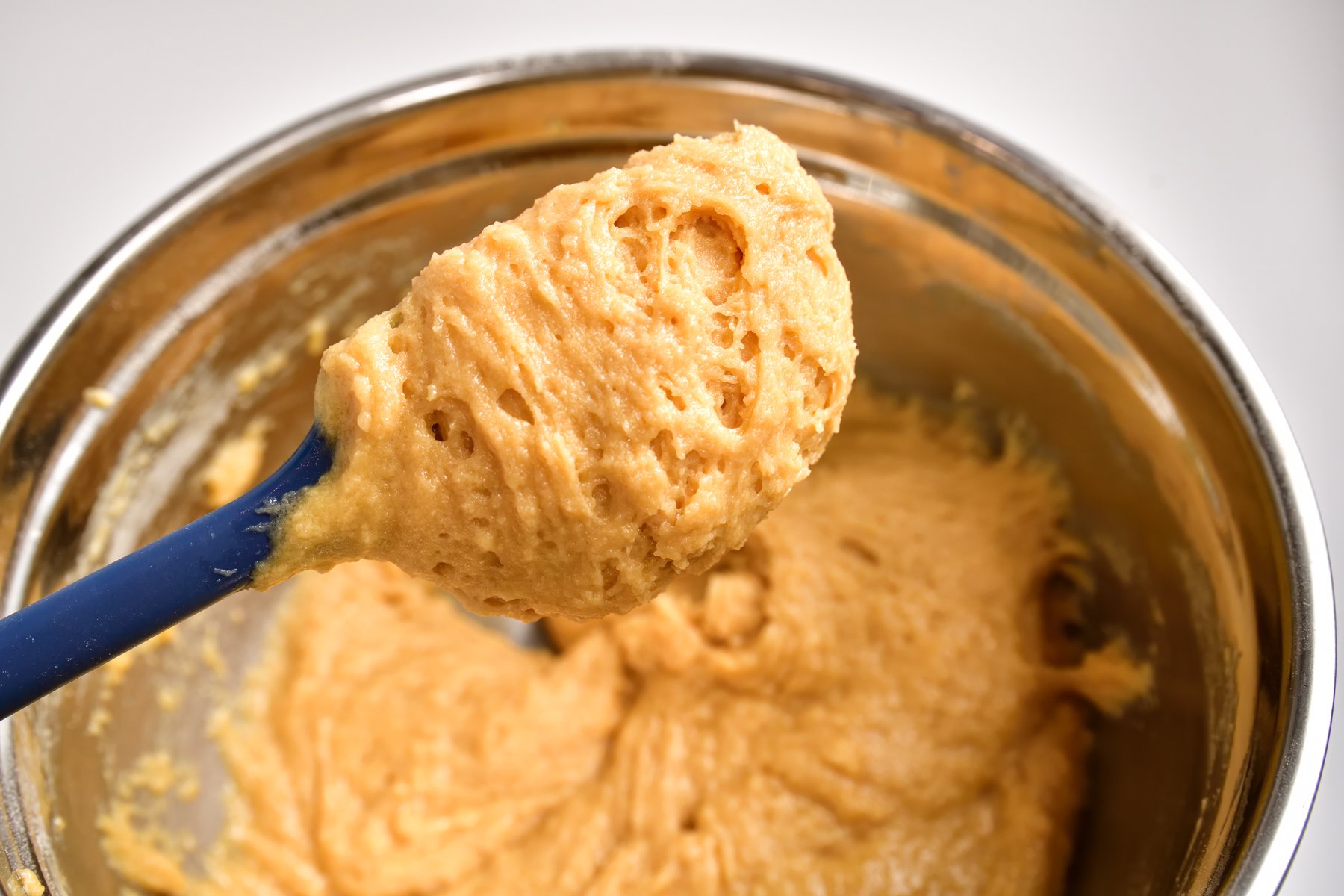 Rhubarb Muffin Batter clinging to a blue rubber spatula to show the batter texture