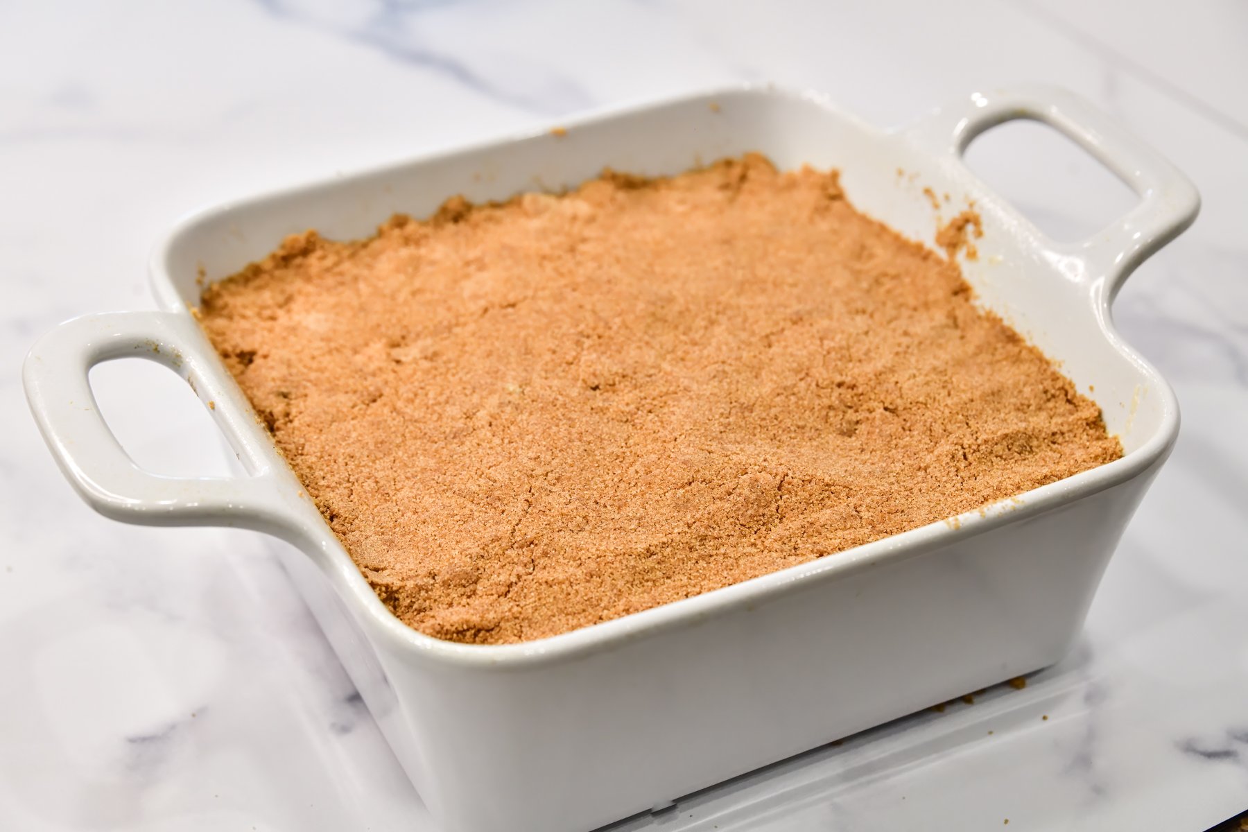 unbaked Rhubarb coffee cake in a white pan with cinnamon streusel spread across the top ready to be baked.