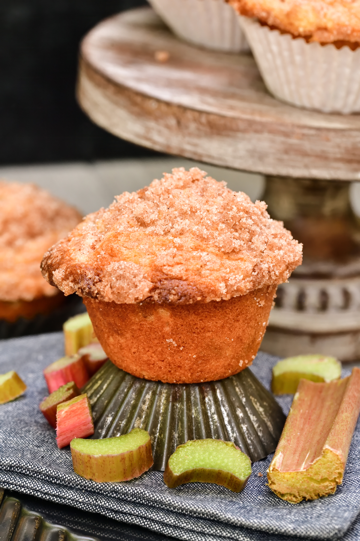 Baked Rhubarb Muffin on an old fashioned tin muffin liner next to chopped rhubarb