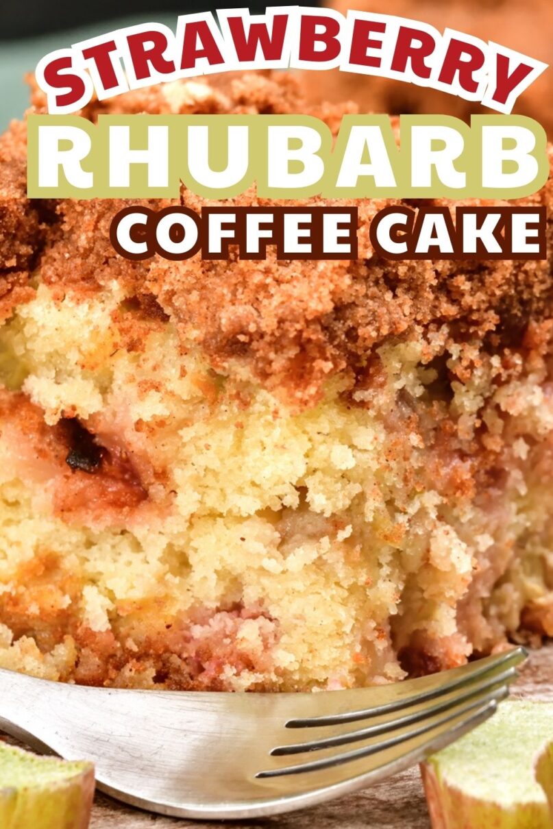 Square slice of coffee cake on a wood platter next to a silver fork and fresh strawberries and rhubarb and a glass of milk in the background with text overlay saying strawberry rhubarb coffee cake