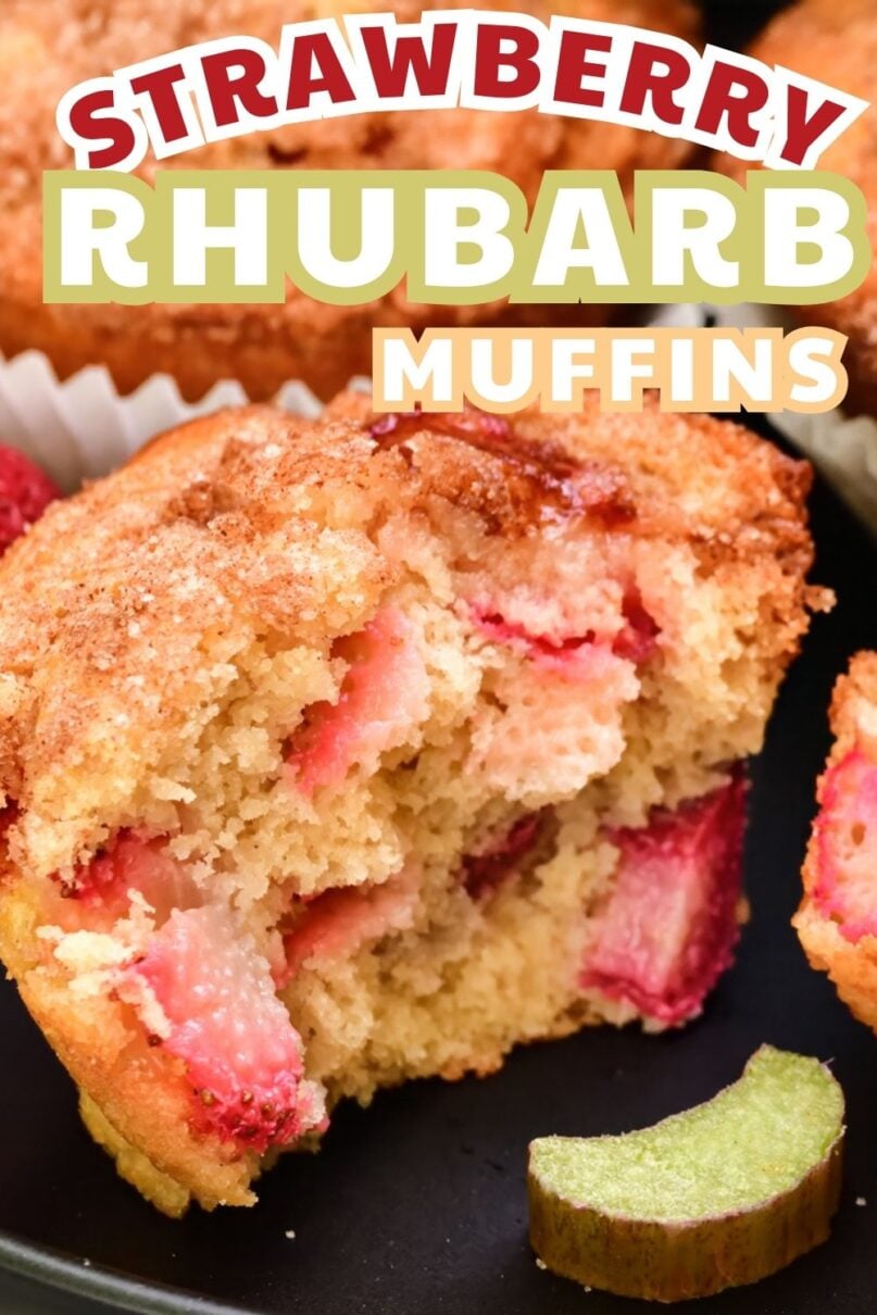 Single muffin on a black plate torn apart displaying chunks of strawberries and rhubarb inside with text overlay saying Strawberry Rhubarb Muffins